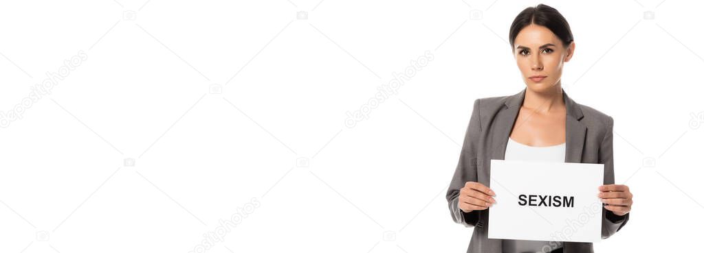 panoramic concept of attractive businesswoman holding placard with sexism lettering isolated on white