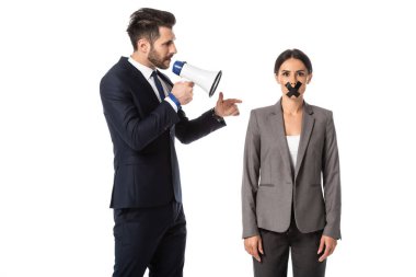 Sakallı iş adamı megafonla bağırıyor ve beyaz ağızlı bir kadını işaret ediyor.