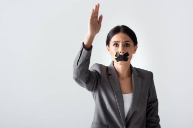 Ağzında selobant olan iş kadını elini kaldırıyor ve beyaz, cinsiyet eşitsizliği kavramında izole edilmiş kameraya bakıyor.