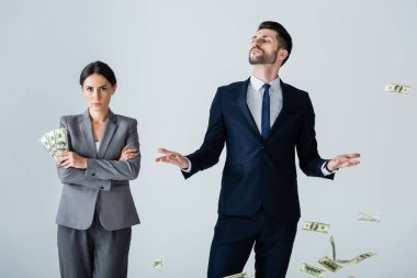 Kibirli iş adamının yanında dolarlar tutan çekici bir iş kadını beyaz adamın üzerinde duruyor.