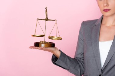cropped view of businesswoman in suit holding golden scales on pink, gender equality concept  clipart
