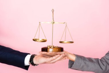 cropped view of businessman and businesswoman holding golden scales isolated on pink, gender equality concept  clipart