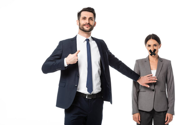 arrogant businessman pointing with finger at himself and touching woman with scotch tape on mouth isolated on white