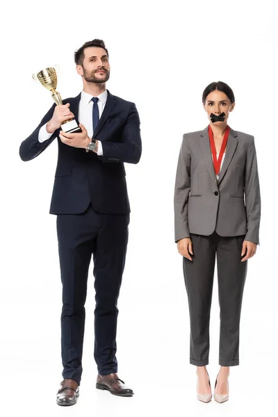 ビジネスウーマンの近くでトロフィーを掲げてるビジネスマンの口にダクトテープとメダル白で隔離された男女不平等の概念 — ストック写真
