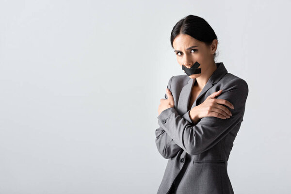 businesswoman with scotch tape on mouth standing with crossed arms isolated on white, gender inequality concept