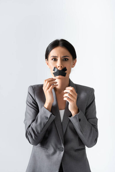 businesswoman with scotch tape on mouth looking at camera isolated on white, gender inequality concept 
