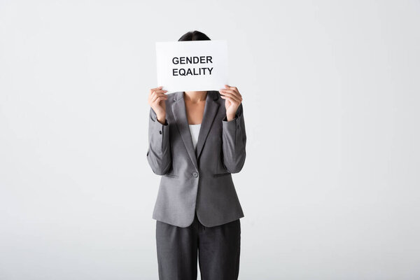 businesswoman covering face while holding placard with gender equality lettering isolated on white 