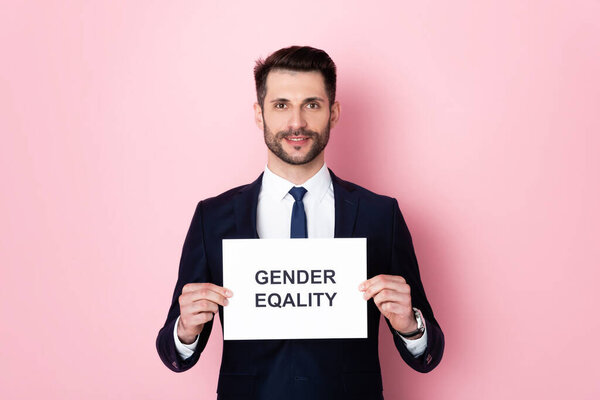 happy businessman holding placard with gender equality lettering on pink 