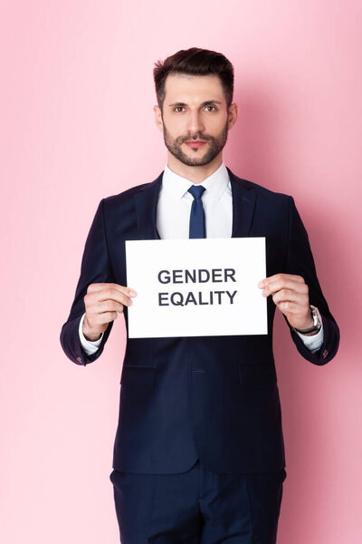 businessman holding placard with gender equality lettering on pink 