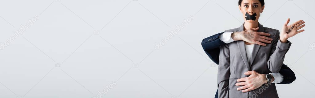panoramic crop of businessman molesting businesswoman with scotch tape on mouth isolated on white