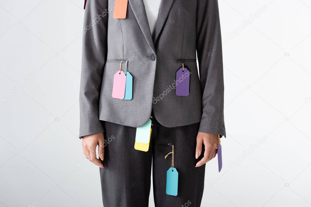 cropped view of businesswoman with labels on formal wear standing isolated on white, gender inequality concept 