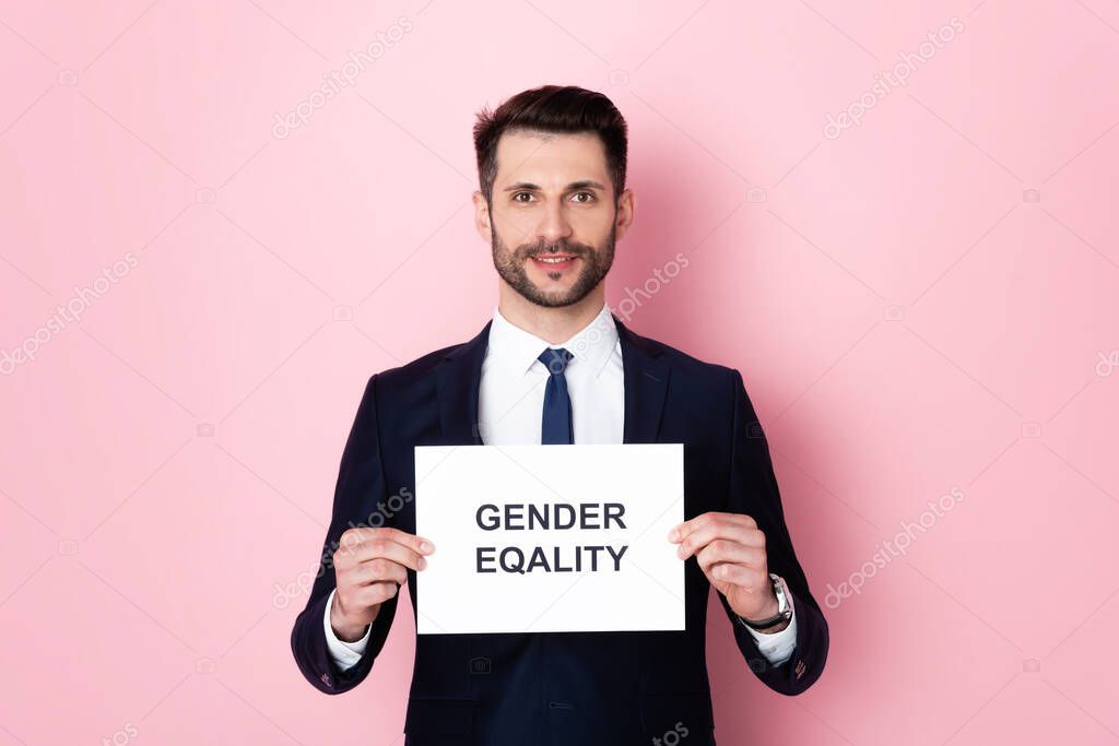 Happy businessman holding placard with gender equality lettering on pink