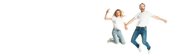 happy adult couple in white t-shirts holding hands while jumping isolated on white, panoramic shot