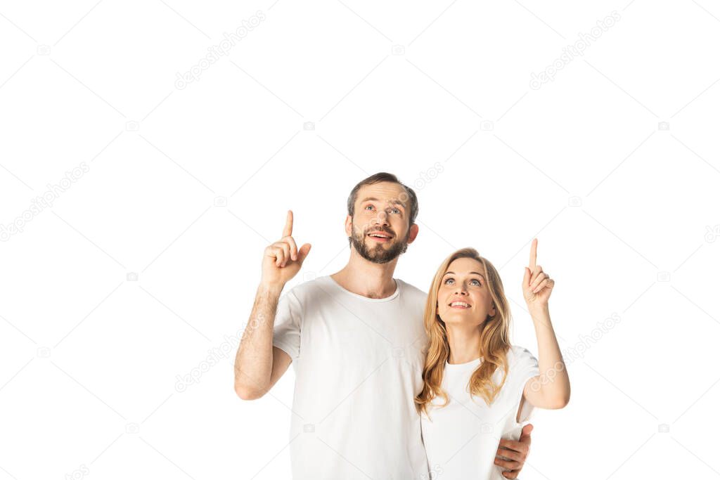 cheerful adult couple in white t-shirts pointing with fingers up isolated on white
