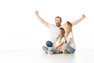 happy family sitting on floor with crossed legs while man showing yes gesture isolated on white clipart