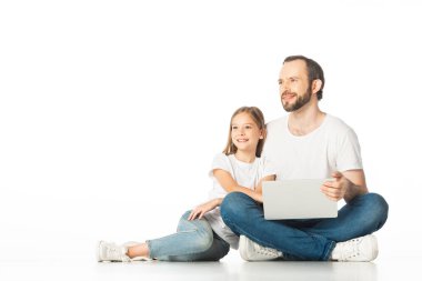 Gülümseyen baba ve kız dizüstü bilgisayarlarıyla beyaz zeminde oturuyorlar.