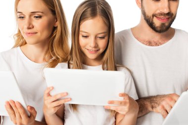 Beyaz tişörtlü gülümseyen aile beyaza izole edilmiş dijital tabletler kullanıyor.