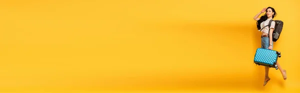 Брюнетка Жінка Стрибає Рюкзаком Валізою Дивиться Жовтий Фон Панорамний Постріл — стокове фото