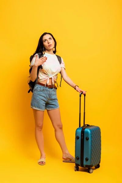 Brünette Frau Mit Rucksack Und Koffer Auf Gelbem Hintergrund — Stockfoto