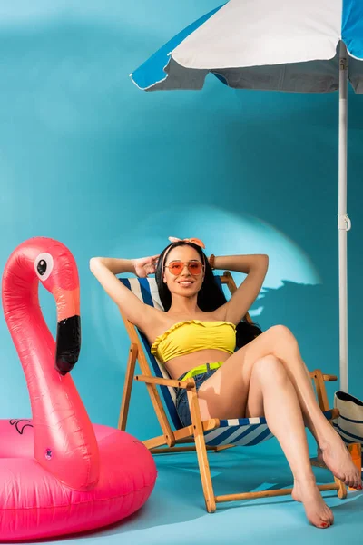 Glimlachend Stijlvol Meisje Zittend Ligstoel Nabij Opblaasbare Flamingo Strandtas Parasol — Stockfoto