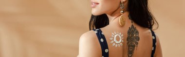 cropped view of woman with drawn sun made of sunscreen and tattoo on back on beige background, panoramic shot clipart