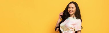 Sarı, panoramik çekimde izole edilmiş saçlara dokunan mutlu esmer kız.