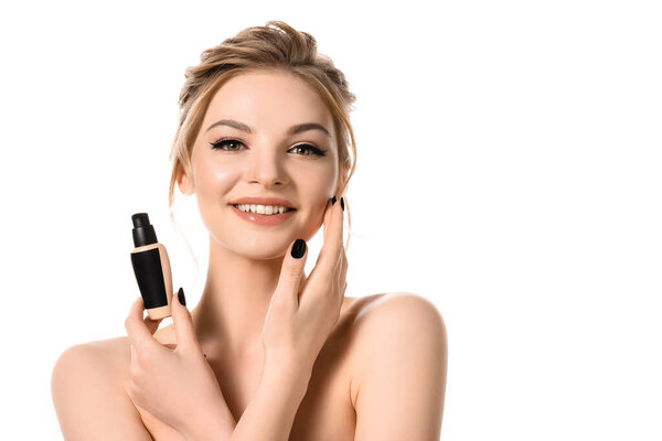 smiling naked beautiful blonde woman with makeup and black nails holding face foundation isolated on white