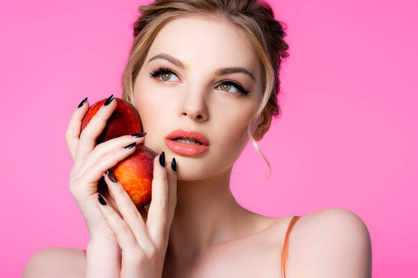 elegant beautiful blonde woman holding peaches isolated on pink
