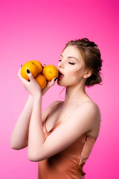 优雅美丽的金发女人舔着成熟的橙子 与粉色隔离 — 图库照片