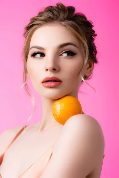エレガントな美しいですブロンド女性ホールディング熟したオレンジ上の肩孤立オンピンク — ストック写真