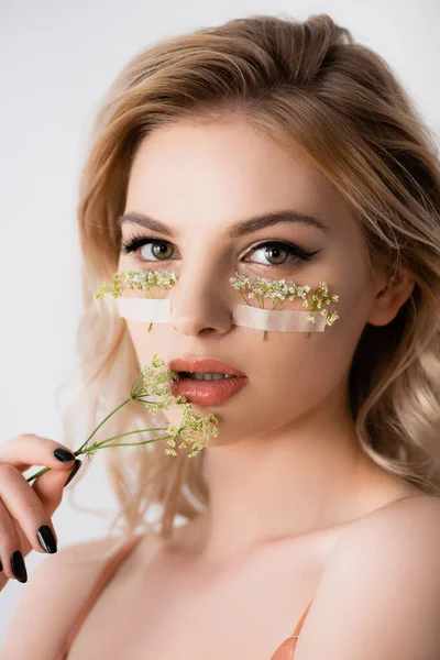 Piękna Blondynka Dzikimi Kwiatami Pod Oczami Blisko Usta Odizolowane Białym — Zdjęcie stockowe