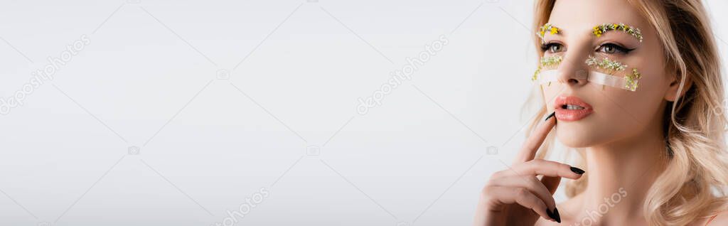 naked beautiful blonde woman in silk dress with wildflowers under eyes looking away isolated on white, panoramic shot