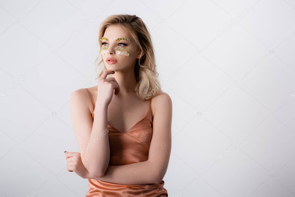 dreamy beautiful blonde woman in silk dress with wildflowers under eyes isolated on white