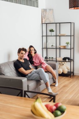 Genç çiftin evdeki kanepede otururken kameraya baktığı seçici odak. 