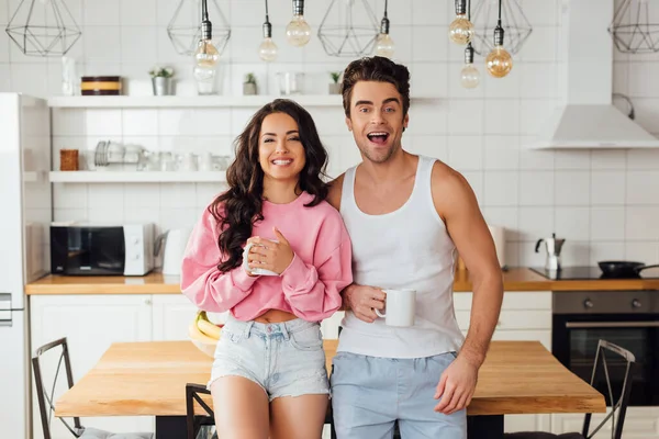Cheerful Couple Cups Coffee Looking Camera Kitchen — Stock Photo, Image