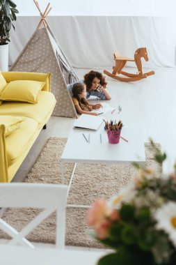 Oyuncak çadırda yatarken bebek bakıcısı ve çocuk çiziminin yüksek açılı görüntüsü