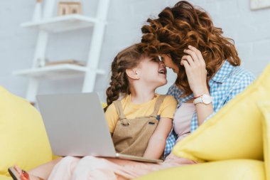 Mutlu dadı ve çocuğun seçici odak noktası kanepede dizüstü bilgisayarla yüz yüze oturması.