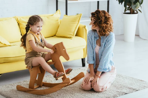 Glücklich Babysitter Sitzt Auf Dem Boden Neben Entzückenden Kind Reiten — Stockfoto