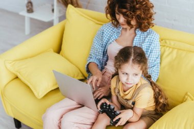 KYIV, UKRAINE - 19 Haziran 2020: Dadı bilgisayarında çalışan sevimli bir çocuğun joystick 'i ile yüksek açılı görüntüsü