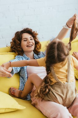 Mutlu bebek bakıcısının koltukta otururken çocuğuyla eğlenmesinin seçici odağı
