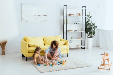 Çocuk bakıcısının ve çocuğun oturma odasındaki çok renkli bloklarla oynamalarının seçici odağı