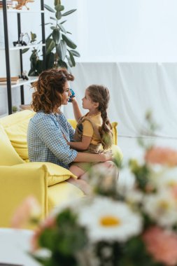Birbirlerine bakarken genç dadının kucağında oturan sevimli çocuğun seçici odağı.