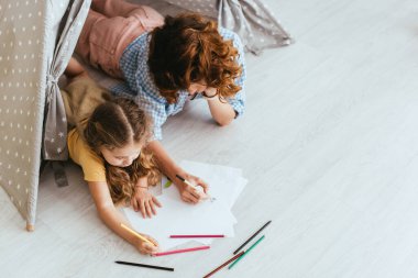 Oyuncak çadırda yatarken çocuk ve dadının çizimlerinin yüksek açılı görüntüsü
