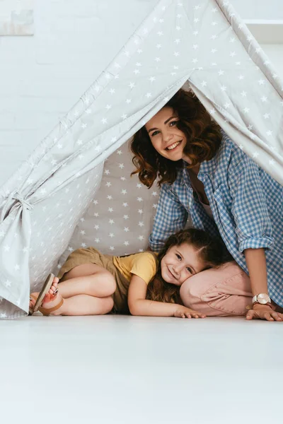 Счастливый Ребенок Лежит Коленях Улыбающейся Няни Игровой Палатке Дома — стоковое фото