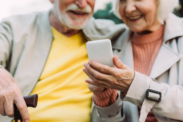 都市部の路上でスマートフォンを使用して高齢者のカップルの笑顔の作物ビュー — ストック写真