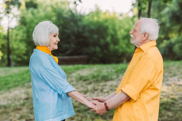 Boční Pohled Seniorku Usmívající Při Držení Rukou Manžela Parku — Stock fotografie