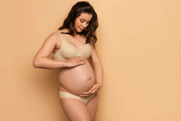 若いです妊娠中の女性で下腹に触れるベージュ — ストック写真
