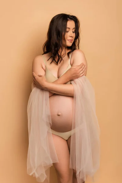 ブルネット妊娠中の女性でランジェリーとシフォンスリーブ巨大自分自身とともに閉じられた目オンベージュ — ストック写真