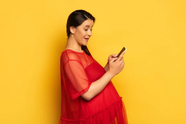 Young Pregnant Woman Red Tunic While Chatting Smartphone Yellow — Stock Photo, Image