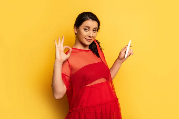 Młoda Kobieta Ciąży Czerwonej Tunice Pokazuje Test Ciążowy Okay Gest — Zdjęcie stockowe